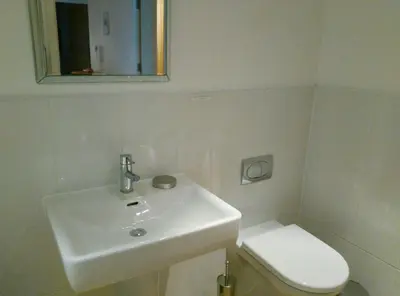 a white bathroom with a sink and a toilet at South Fistral Seaview 2-bed Apartment in Newquay