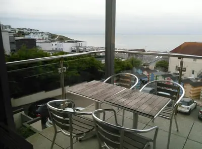 a table and chairs on a balcony with a view of the ocean at South Fistral Seaview 2-bed Apartment in Newquay