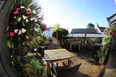 an outdoor patio with a wooden table and flowers at Victoria Inn in Penzance