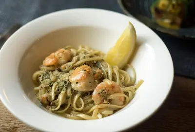 a bowl of pasta with shrimp and a lemon wedge at Victoria Inn in Penzance