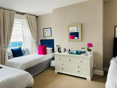 a bedroom with two beds and a white dresser at Molesworth Arms in Wadebridge