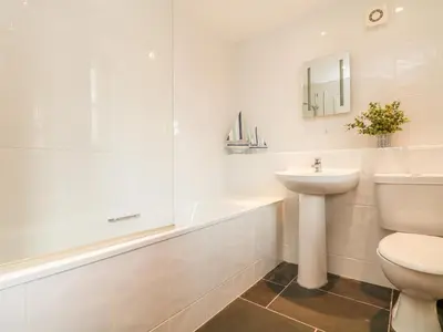 a bathroom with a sink and a toilet and a tub at Ash Cottage in Truro