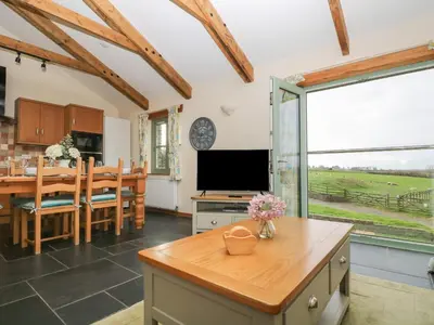 a kitchen and dining room with a table and a television at Ash Cottage in Truro