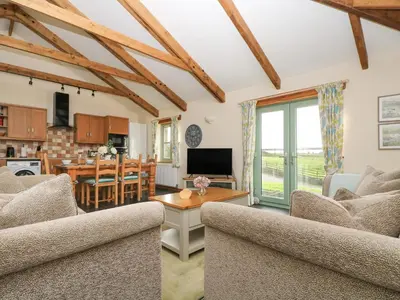 a living room with two couches and a table at Ash Cottage in Truro