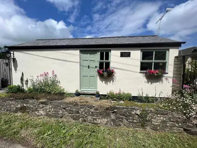 a white cottage with flowers in the window at Palmers Lodge in Launceston