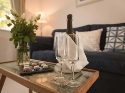a table with two wine glasses and a bottle on it at Kilcarreg in Wadebridge