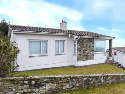 a white house with a stone wall at Godolphin in Wadebridge