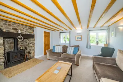a living room with a couch and a fireplace at Penbarden Barn in Bude