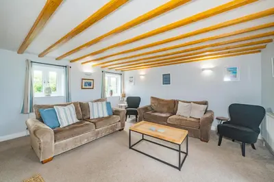 a living room with two couches and a table at Penbarden Barn in Bude