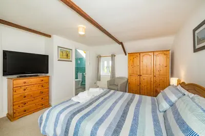 a bedroom with a bed and a flat screen tv at Penbarden Barn in Bude