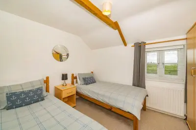 a bedroom with two beds and a window at Penbarden Barn in Bude