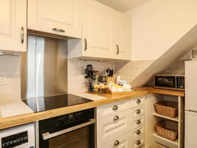 a kitchen with white cabinets and black appliances at Penrose Farm Cottage in Saint Keverne