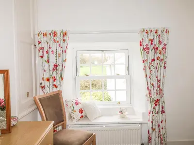 a window with curtains and a radiator in a room at Penrose Farm Cottage in Saint Keverne