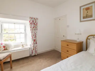 a bedroom with a window and a bed and a dresser at Penrose Farm Cottage in Saint Keverne