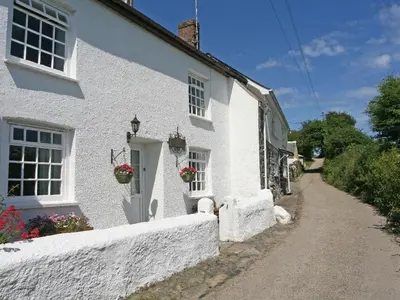 a white house with flower pots on the door at Penrose Farm Cottage in Saint Keverne