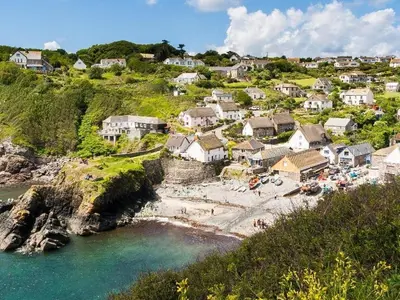 a village with a beach and houses on a hill at Penrose Farm Cottage in Saint Keverne