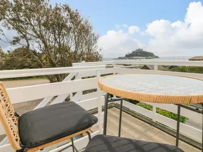 a table and chairs on a balcony with a view of the ocean at Sea Breeze in Marazion