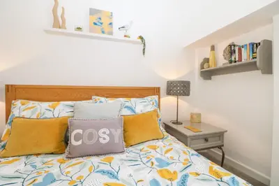 a bedroom with a bed with yellow and blue pillows at Sea Breeze in Marazion
