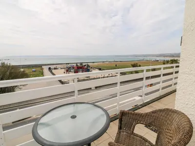 a table and chairs on a balcony with a view of the beach at Sea Breeze in Marazion