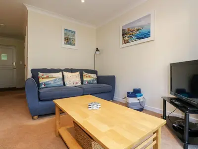 a living room with a blue couch and a table at Fox's Walk in Falmouth