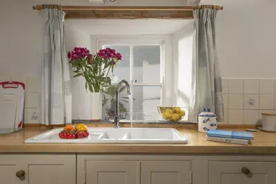 a kitchen sink with a vase of flowers next to a window at Trevara, Marazion in Marazion