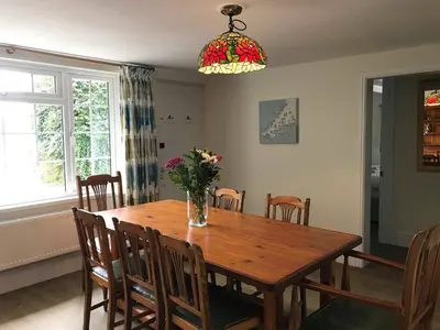 a dining room table with chairs and a vase of flowers at Bejowan Cornish Cottage in Newquay