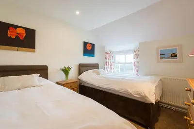 a bedroom with two beds and a window at Bejowan Cornish Cottage in Newquay