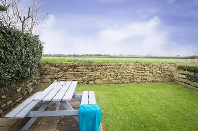 a white bench sitting in a yard next to a stone wall at Bejowan Cornish Cottage in Newquay