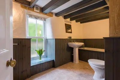 a bathroom with a toilet and a sink and a window at Bejowan Cornish Cottage in Newquay