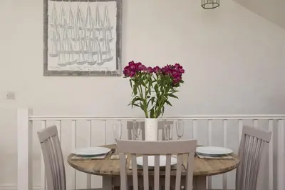 a dining room table with a vase of purple flowers at Little Trevara, Marazion in Marazion