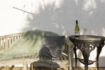 a chair with a pillow next to a table with a bottle of wine at Little Trevara, Marazion in Marazion