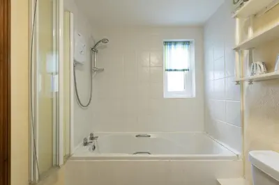 a white bathroom with a tub and a shower at Little Trevara, Marazion in Marazion