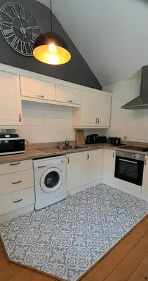 a kitchen with a washer and dryer on a rug at Stunning cosy barn in peaceful rural Cornwall in Truro
