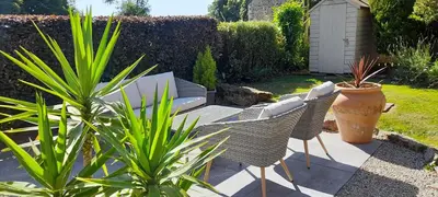 a patio with chairs and plants in a garden at Stunning cosy barn in peaceful rural Cornwall in Truro