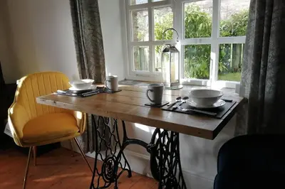 a wooden table with two bowls on it next to a window at Stunning cosy barn in peaceful rural Cornwall in Truro