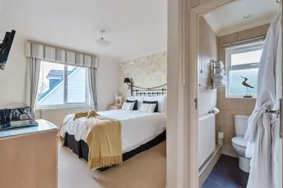 a bedroom with a bed and a toilet and a window at Lamorna Lodge in St Ives