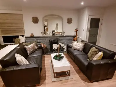 a living room with a leather couch and a fireplace at Lamorna Lodge in St Ives