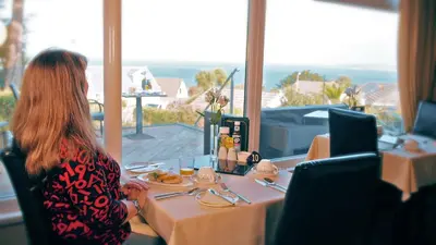 a woman sitting at a table with a plate of food at Lamorna Lodge in St Ives