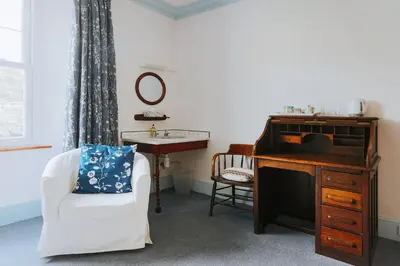 a room with a piano and a chair and a sink at Ivy House Cornwall B&B in St Austell