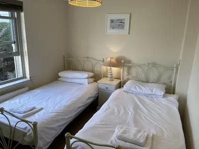two beds in a bedroom with a lamp on a night stand at Lews Lookout in St Ives