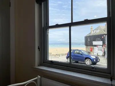 a window with a view of the beach and a blue car at Lews Lookout in St Ives
