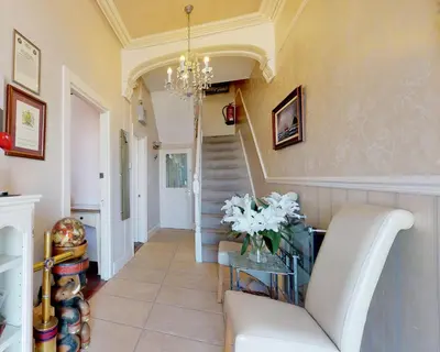 a hallway with a white couch and a chandelier at Golden Hind in St Ives