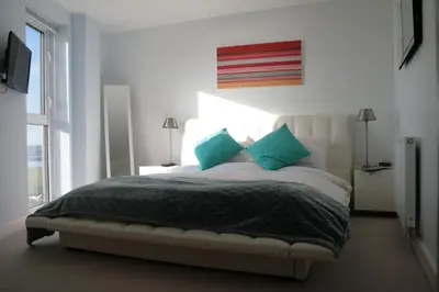 a bedroom with a large bed with blue pillows at 19 Ocean Gate in Newquay