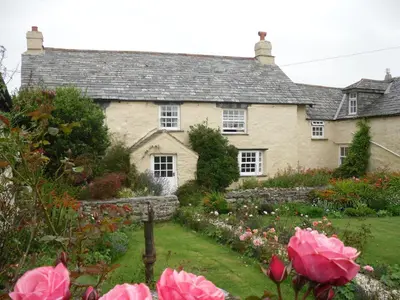 a house with a garden and pink flowers at Higher Tresmorn Farm in Crackington Haven