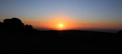 a sunset with the sun setting over the ocean at Higher Tresmorn Farm in Crackington Haven