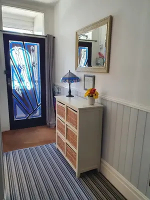 a room with a dresser and a mirror and a door at Westward B&B in Newquay