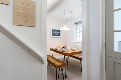 a dining room with a table and a stairway at Stylish Two Bedroom Cottage - In Town Centre in St Ives