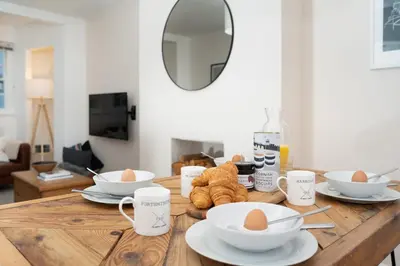a wooden table with eggs in bowls and cups on it at Stylish Two Bedroom Cottage - In Town Centre in St Ives