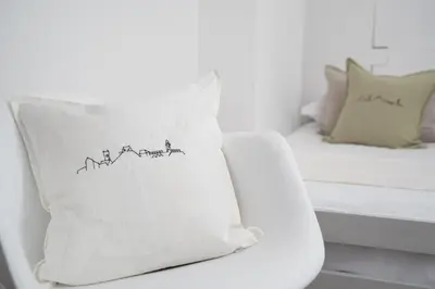 a white couch with a pillow with a drawing on it at Stylish Two Bedroom Cottage - In Town Centre in St Ives