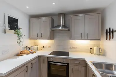 a kitchen with white cabinets and a stove top oven at Stylish Two Bedroom Cottage - In Town Centre in St Ives